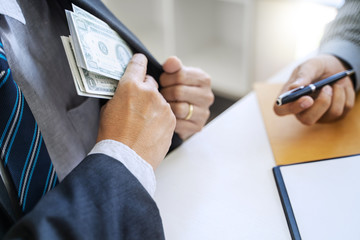 business people giving bribe money in an office.
