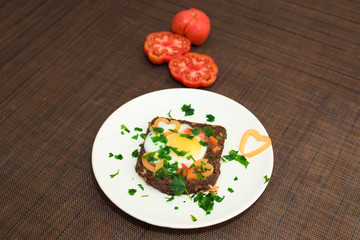 egg in bread with herbs and tomatoes on a Breakfast plate