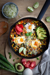 Shakshuka, huevos fritos en salsa de tomate y verduras sobre fondo de madera. Comida sana.