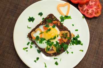 egg in bread with herbs and tomatoes on a Breakfast plate