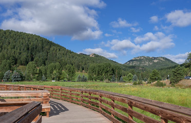 Landscape of wooden walkway, marsh or meadow land and mountains at Dedisse Park in Evergreen, Colorado