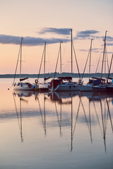 Fototapeta na wymiar Yachts and boats moored in a harbour at sunrise. Candid people, real moments, authentic situations