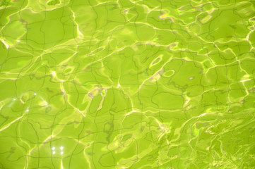 Swimming pool bottom caustics ripple and flow with waves background. Summer background. Texture of water surface.