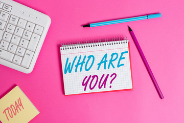 Conceptual hand writing showing Who Are You question. Concept meaning asking about demonstrating identity or demonstratingal information Writing equipments and computer stuff placed on wooden table