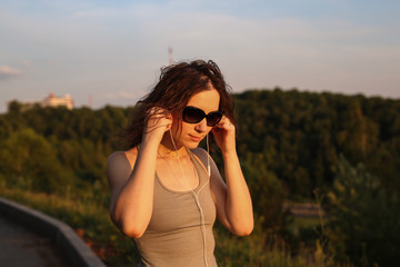 woman in sunglasses with headphones in the park