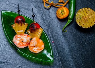 Fototapeta na wymiar Grilled Shrimps And Bell Peppers On Skewers With Cherry Tomatoes Halves On Green Tray