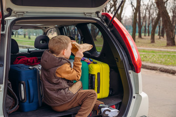 little kid looking into paper bag with candies sitting in car trunk