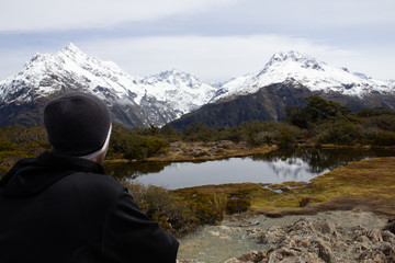 Fototapeta premium Milford Sound Summit Trek Man looking at a beautiful view of mountains at summit