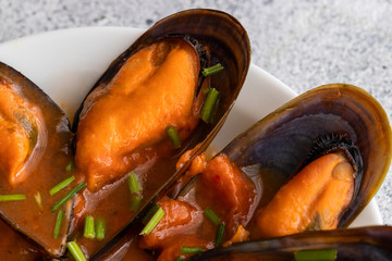 Close up of mussels cooking in herb sauce on the table. Seafood dish background..