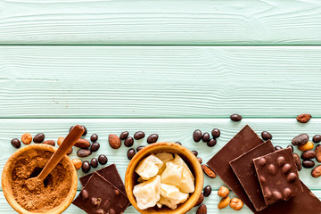 Cook homemade chocolate with bars, nuts, coffee beans on mint green wooden background top view mock up
