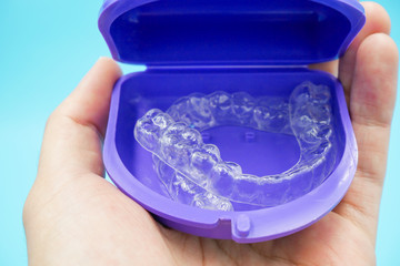 clear plastic retainer teeth in the box set isolated on blue sky background. it's an equipment for orthodontist give the patient to orthodontic surgery in dental clinic or hospital