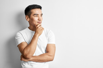 Portrait of smart thinking Kazakh man dressed in casual on white background. Asian handsome student in studio