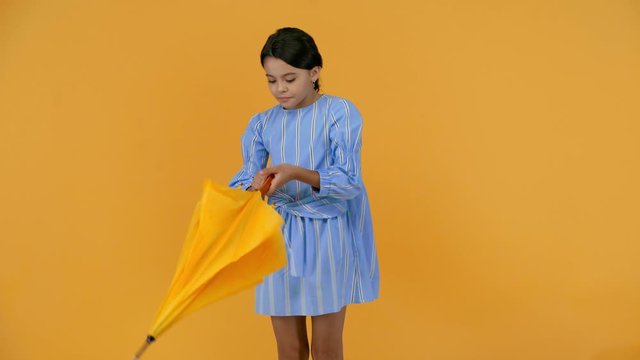 happy preteen child in blue dress with yellow umbrella