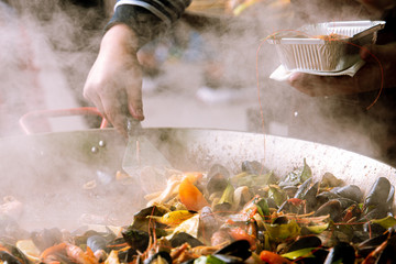 Seafood and pepper are cooked in a large cauldron