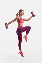 Athletic woman jumping with dumbbells