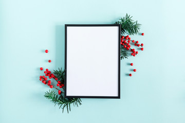 Christmas modern composition. Photo frame, red berries on pastel blue background. Christmas, New Year, winter concept. Flat lay, top view, copy space