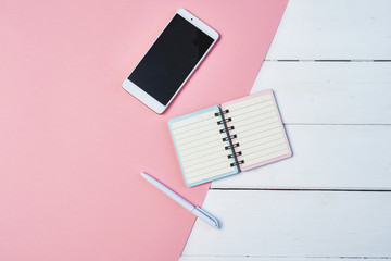 Mockup Flat lay composition with smartphone and notepad on a blue and pink background. Desktop with copy space