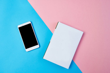 Mockup Flat lay composition with smartphone and notepad on a blue and pink background.