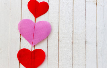 Red and Pink hearts and on white wooden blackground