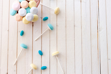 Soft colors suck chup and blue jelly beans on white wooden blackground.