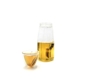 Clear glass jug and cup with herb tea on white background.