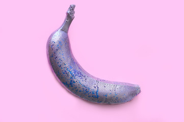 Silver colored banana in banana on a pink background. Silver color metal food. Tropical flat lay. Creative concept