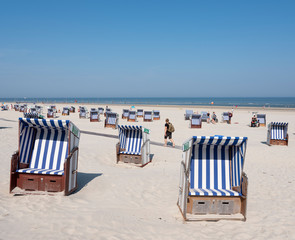 man with rucksack passes beach korbs on the island of norderney in germany on sunny day