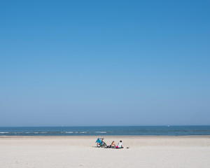 Fototapeta na wymiar few people on large sandy beach of german island norderney off the coast of ostfriesland under blue august sky