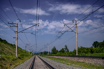 Double-track railway on a summer morning with the contact lines