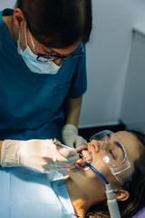 process of placing white dental braces to a Caucasian girl in a dental clinic with a dentist girl
