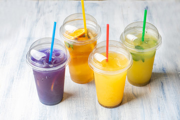 Different types of cold summer, natural lemonade in plastic glass on blue background. Set of refreshing drinks
