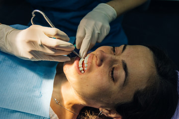 process of placing white dental braces to a Caucasian girl in a dental clinic with a dentist girl