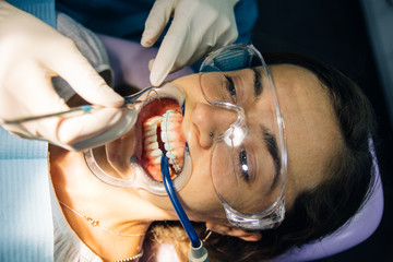 process of placing white dental braces to a Caucasian girl in a dental clinic with a dentist girl