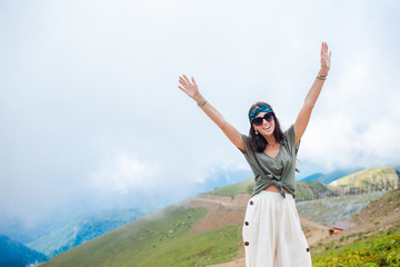Beautiful happy young woman in mountains in the background of fog