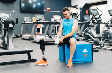Fototapeta premium Disabled athlete assembling his leg prosthesis in the gym. Paralympic Sport Concept.