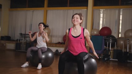 Athletic womans trains in the fitness room with gymnastic ball.