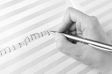 Hand writing music notes close-up in black and white