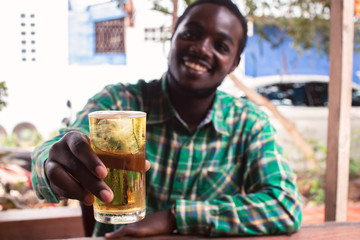 Fototapeta na wymiar African man smiling and holding a glass of beer