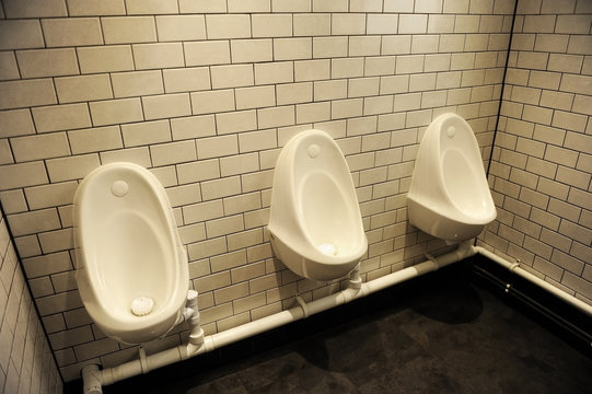 Tres urinarios de porcelana blanca en un ba&ntilde;o p&uacute;blico en Londres, Inglaterra, Reino Unido