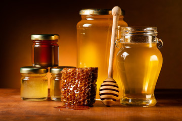 Various types of honey in glass jars with ladle and honeycomb. Still life