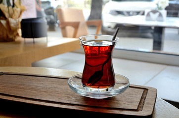 Turkish tea, a glass with tea on a wooden tray in a cafe.