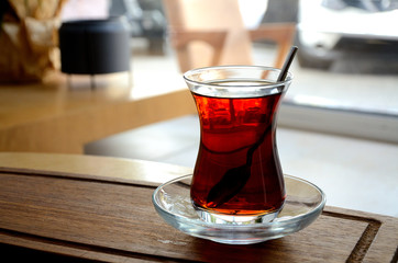 Turkish tea, a glass with tea on a wooden tray in a cafe.