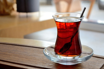 Turkish tea, a glass with tea on a wooden tray in a cafe.