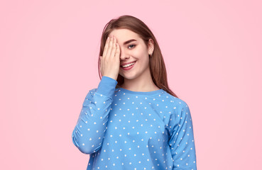 Cheerful teenager in pajama covering eye