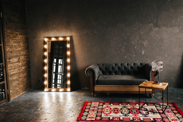 Corner room with a wooden and  gray cement wall, an aged floor, black glass doors and electric...