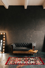 Corner room with a wooden and  gray cement wall, an aged floor, black glass doors and electric...