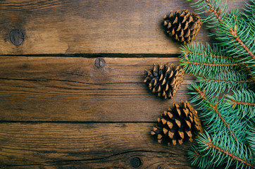 Christmas decoration tree green fir branch with cones on wooden background. Top view, copy space