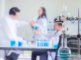 close up scientific equipment in chemical laboratory with blurred scientist background