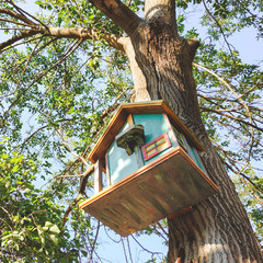 Beautiful decorated birdhouse in a park on a tree