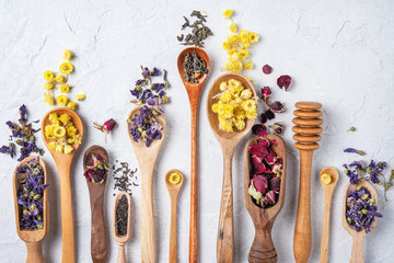 some wood spoon with herbal tea lavender, rose and chamomile on light wood table top view